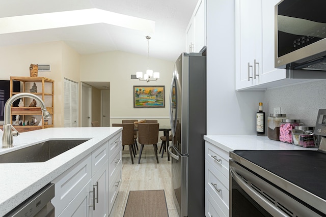 kitchen with stainless steel appliances, vaulted ceiling, sink, pendant lighting, and white cabinetry