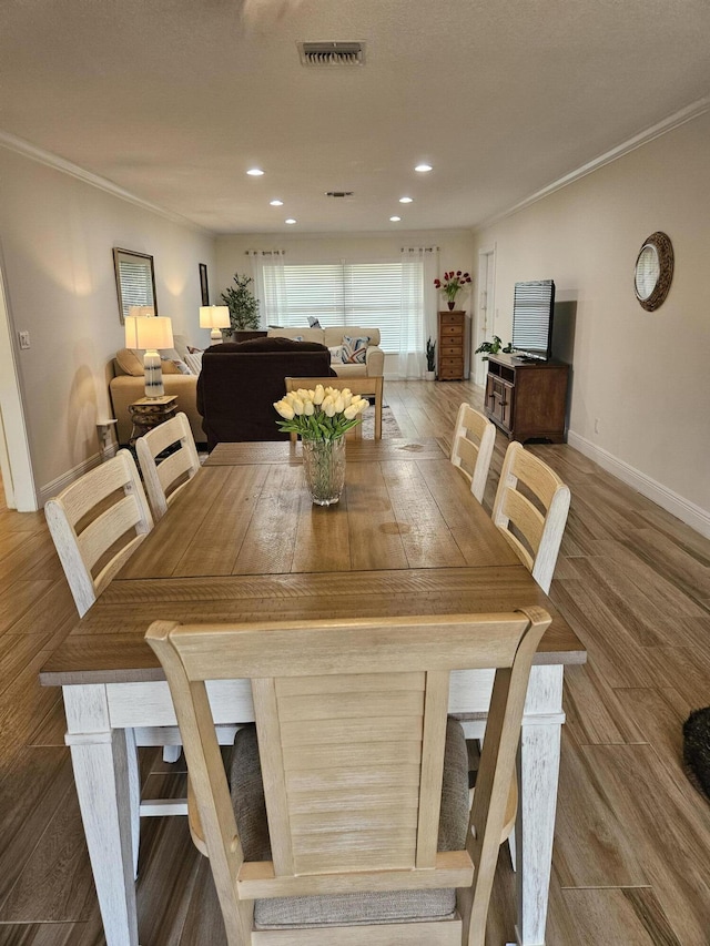 dining space featuring hardwood / wood-style flooring and ornamental molding