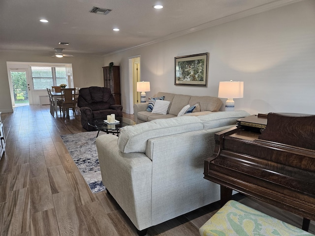 living room with ornamental molding, ceiling fan, and dark wood-type flooring