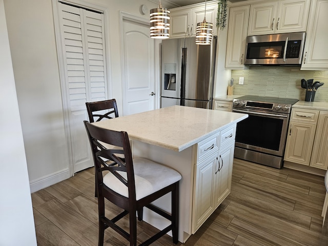 kitchen featuring hanging light fixtures, decorative backsplash, a kitchen island, a kitchen bar, and stainless steel appliances