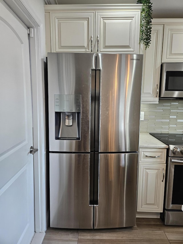 kitchen featuring light stone countertops, backsplash, appliances with stainless steel finishes, and light hardwood / wood-style flooring