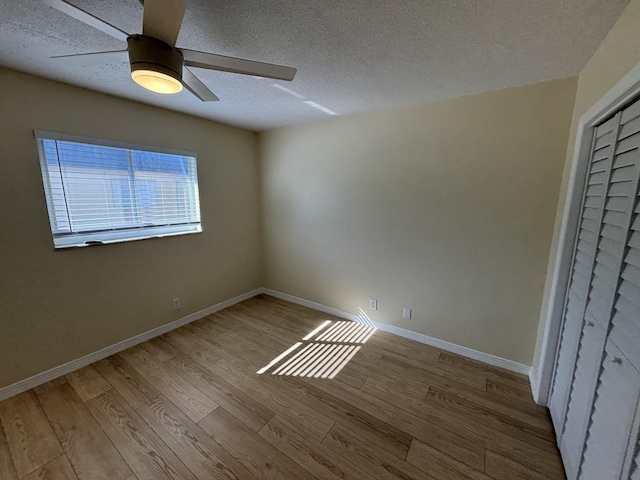 unfurnished bedroom with ceiling fan, light hardwood / wood-style floors, a textured ceiling, and a closet