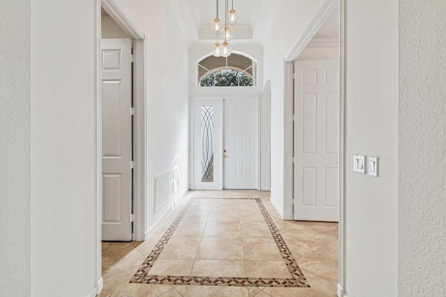 foyer with french doors, light tile patterned floors, ornamental molding, and a notable chandelier