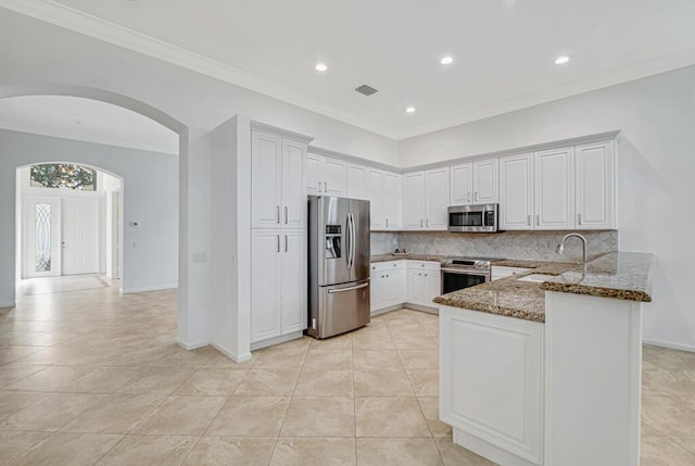 kitchen featuring white cabinets, sink, dark stone countertops, appliances with stainless steel finishes, and kitchen peninsula