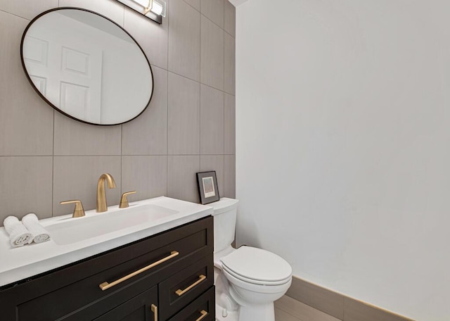 bathroom featuring vanity, toilet, and tile walls