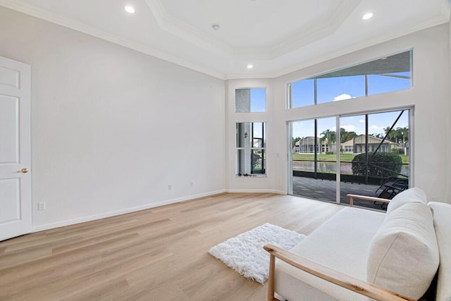 sitting room with a tray ceiling, light hardwood / wood-style flooring, and ornamental molding