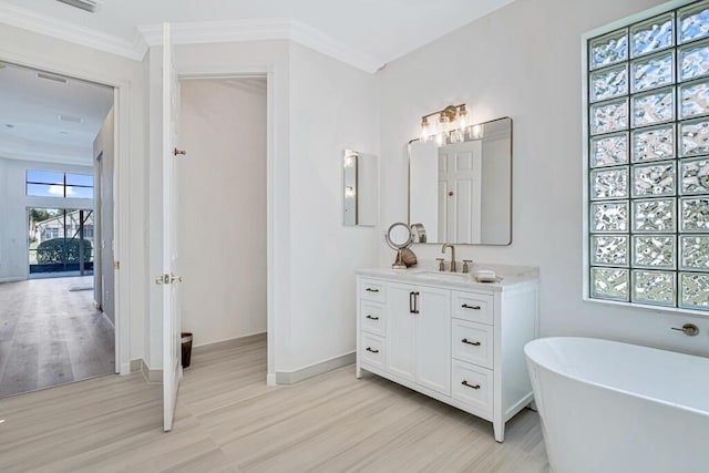 bathroom featuring hardwood / wood-style floors, vanity, a bathing tub, and crown molding