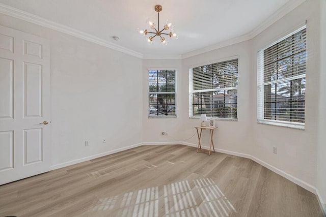 spare room with a healthy amount of sunlight, light wood-type flooring, crown molding, and an inviting chandelier