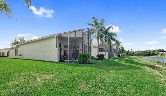 back of property with a lawn, a water view, and a lanai