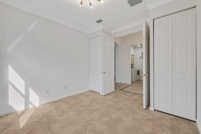 unfurnished bedroom with a closet, light tile patterned floors, ornamental molding, washer / clothes dryer, and a chandelier