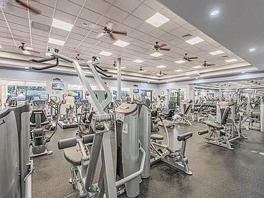 exercise room with a drop ceiling and ceiling fan