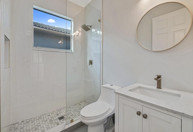 bathroom featuring a tile shower, vanity, and toilet