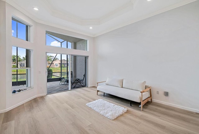 sitting room featuring light hardwood / wood-style floors, a tray ceiling, and crown molding