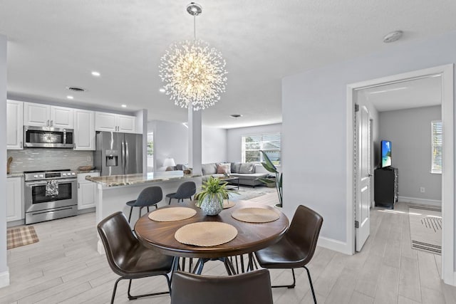 dining space featuring light hardwood / wood-style flooring and a notable chandelier