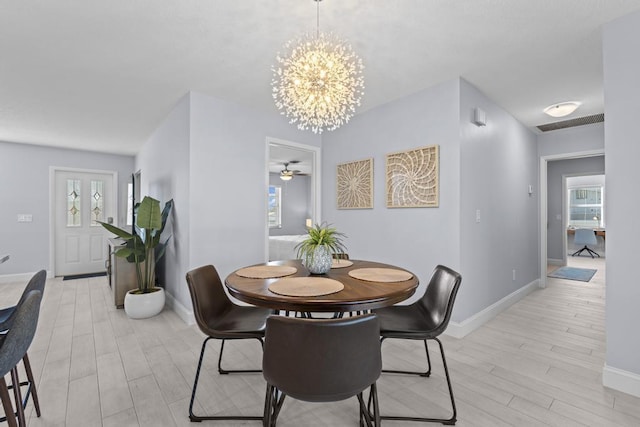 dining area featuring plenty of natural light, light wood-type flooring, and ceiling fan with notable chandelier