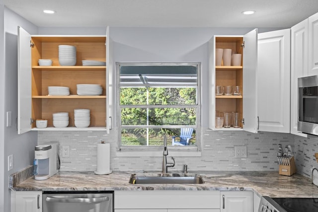 kitchen with light stone countertops, white cabinetry, sink, and stainless steel appliances