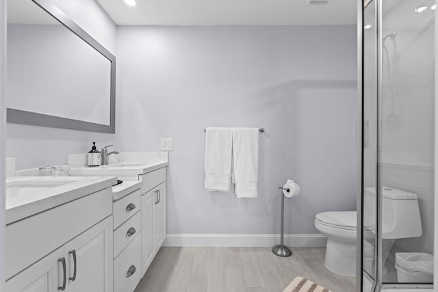 bathroom featuring hardwood / wood-style flooring, vanity, a shower with shower door, and toilet