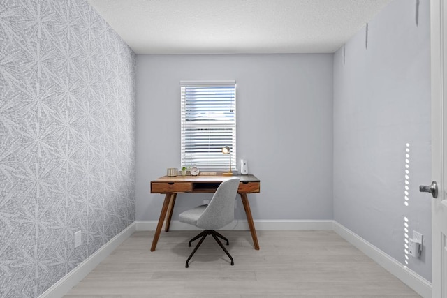 home office with light hardwood / wood-style flooring and a textured ceiling