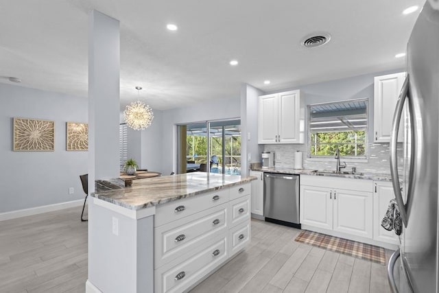 kitchen with white cabinets, stainless steel appliances, a healthy amount of sunlight, and sink