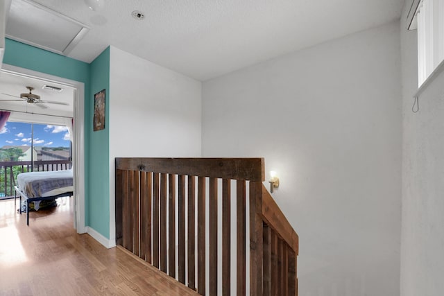 corridor with a textured ceiling and hardwood / wood-style flooring