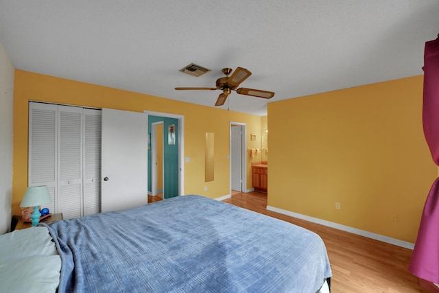 bedroom with ceiling fan, light hardwood / wood-style floors, ensuite bathroom, and a closet