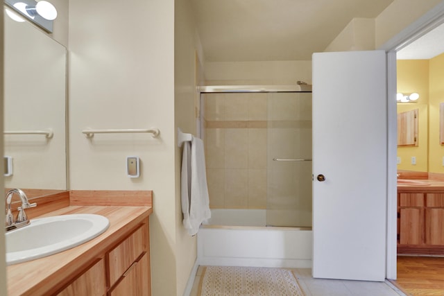 bathroom with vanity, hardwood / wood-style flooring, and bath / shower combo with glass door