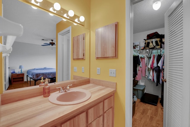 bathroom with vanity, ceiling fan, wood-type flooring, and a textured ceiling