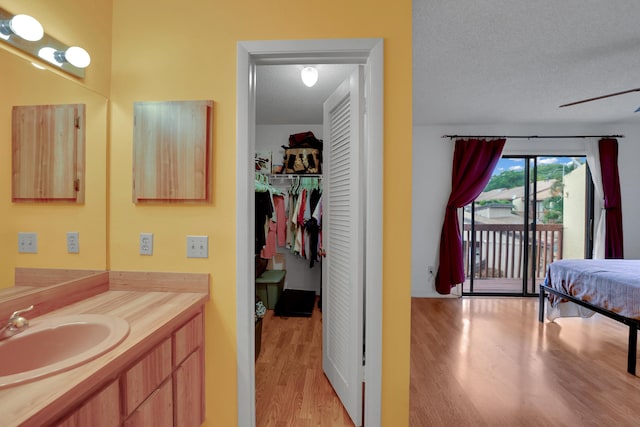 bathroom featuring ceiling fan, hardwood / wood-style floors, vanity, and a textured ceiling