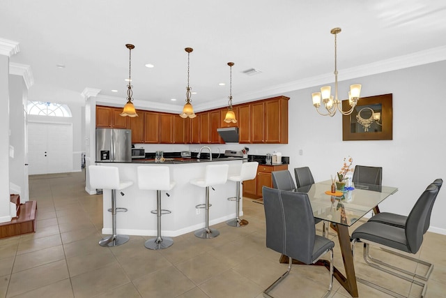 kitchen featuring a breakfast bar area, a center island with sink, stainless steel appliances, and decorative light fixtures