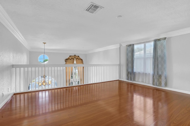 unfurnished room featuring crown molding, wood-type flooring, and a textured ceiling