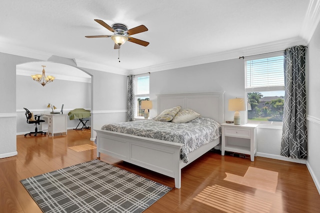 bedroom with ceiling fan with notable chandelier, wood-type flooring, and ornamental molding