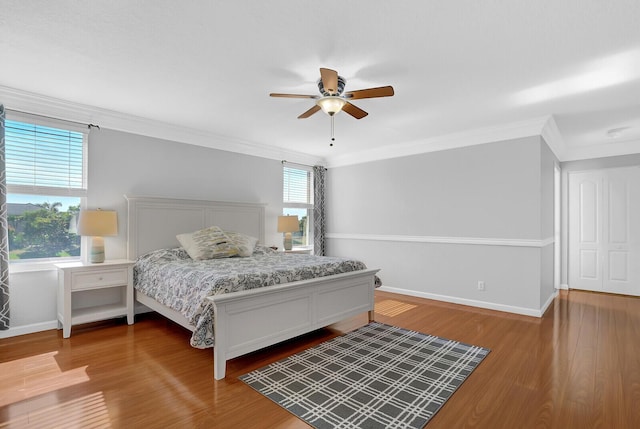 bedroom featuring hardwood / wood-style floors, ceiling fan, ornamental molding, and multiple windows