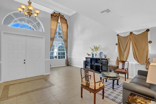 foyer with a chandelier, light tile patterned floors, ornamental molding, and a high ceiling