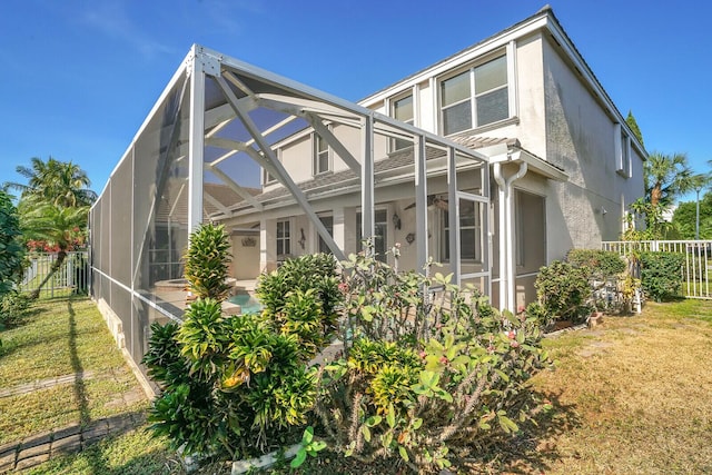 exterior space featuring glass enclosure and a lawn