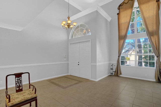 foyer entrance with a high ceiling, an inviting chandelier, crown molding, and light tile patterned flooring