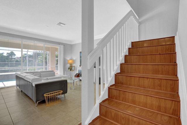 stairway with tile patterned floors and crown molding