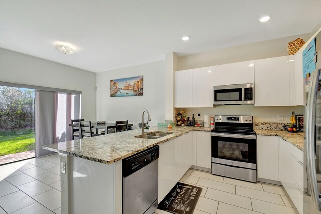 kitchen with light stone countertops, sink, light tile patterned flooring, white cabinets, and appliances with stainless steel finishes