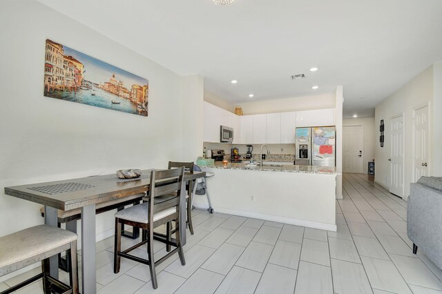 kitchen with white cabinetry, sink, stainless steel dishwasher, and light stone counters