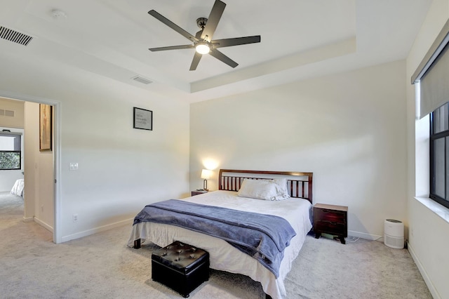 carpeted bedroom featuring a raised ceiling and ceiling fan