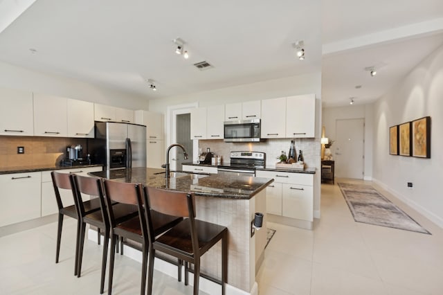 kitchen with a center island with sink, decorative backsplash, sink, and stainless steel appliances