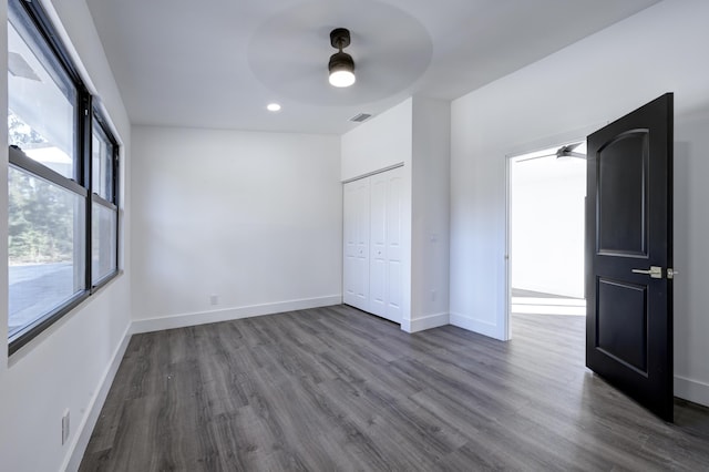 unfurnished bedroom with a closet, dark wood-type flooring, and ceiling fan