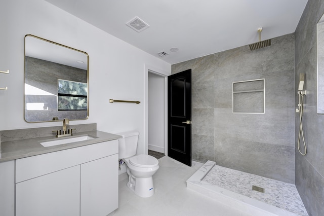 bathroom with vanity, toilet, and tiled shower