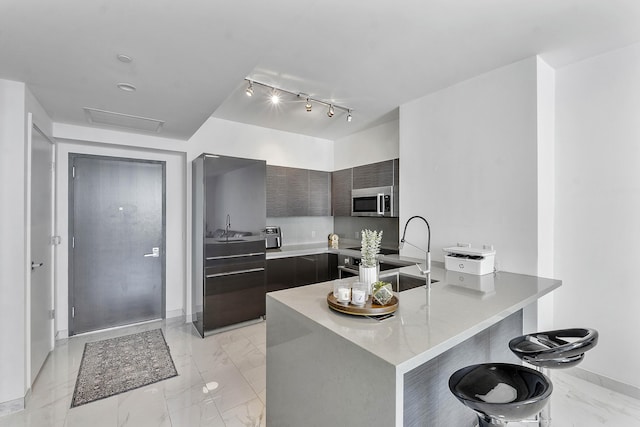 kitchen with a breakfast bar, dark brown cabinetry, kitchen peninsula, and sink