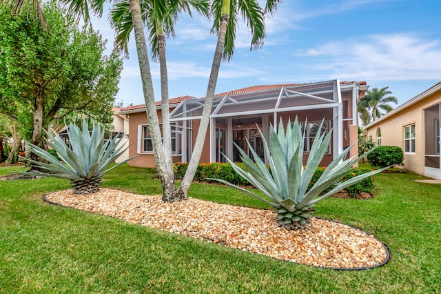 view of front of home featuring glass enclosure and a front lawn