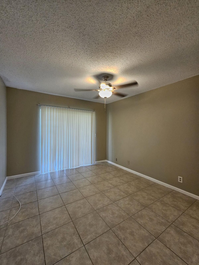 empty room with ceiling fan, light tile patterned flooring, and a textured ceiling