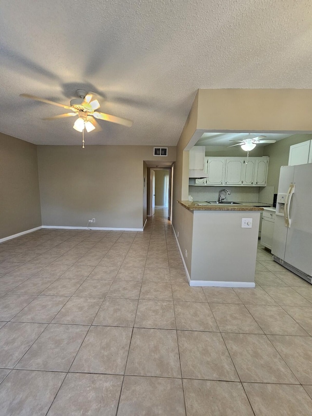 kitchen with white refrigerator with ice dispenser, white cabinets, sink, a textured ceiling, and kitchen peninsula