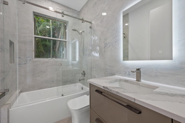 full bathroom with backsplash, bath / shower combo with glass door, toilet, vanity, and tile walls