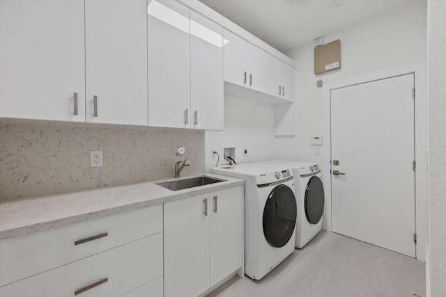 clothes washing area with washer and clothes dryer, cabinets, and sink