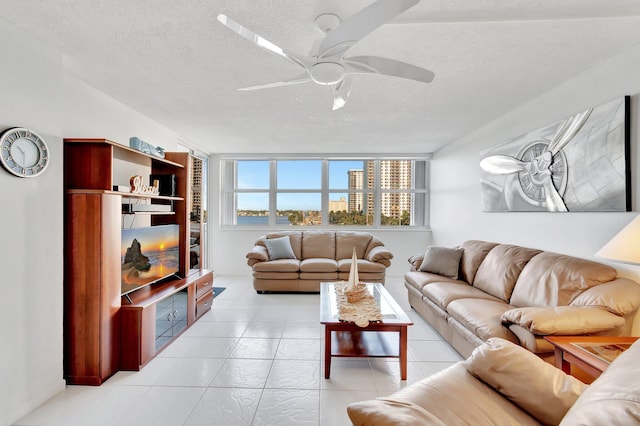 living room with ceiling fan, light tile patterned flooring, and a textured ceiling