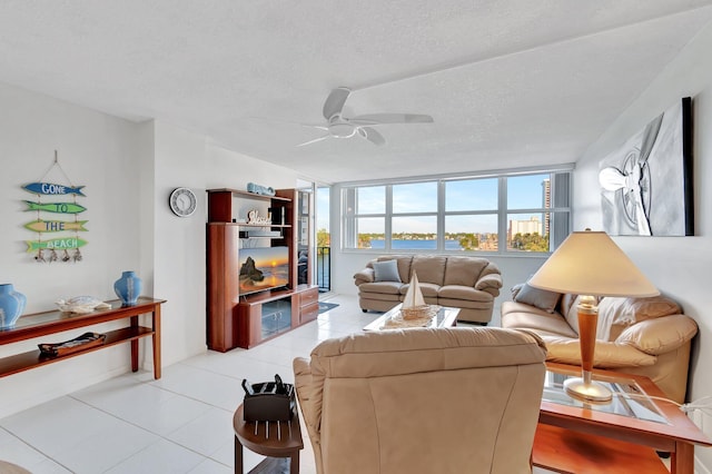 living room with ceiling fan, light tile patterned flooring, and a textured ceiling